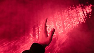 A human hand raised under red lighting.