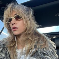 A photo of a woman with a shag hairstyle wearing sunglasses