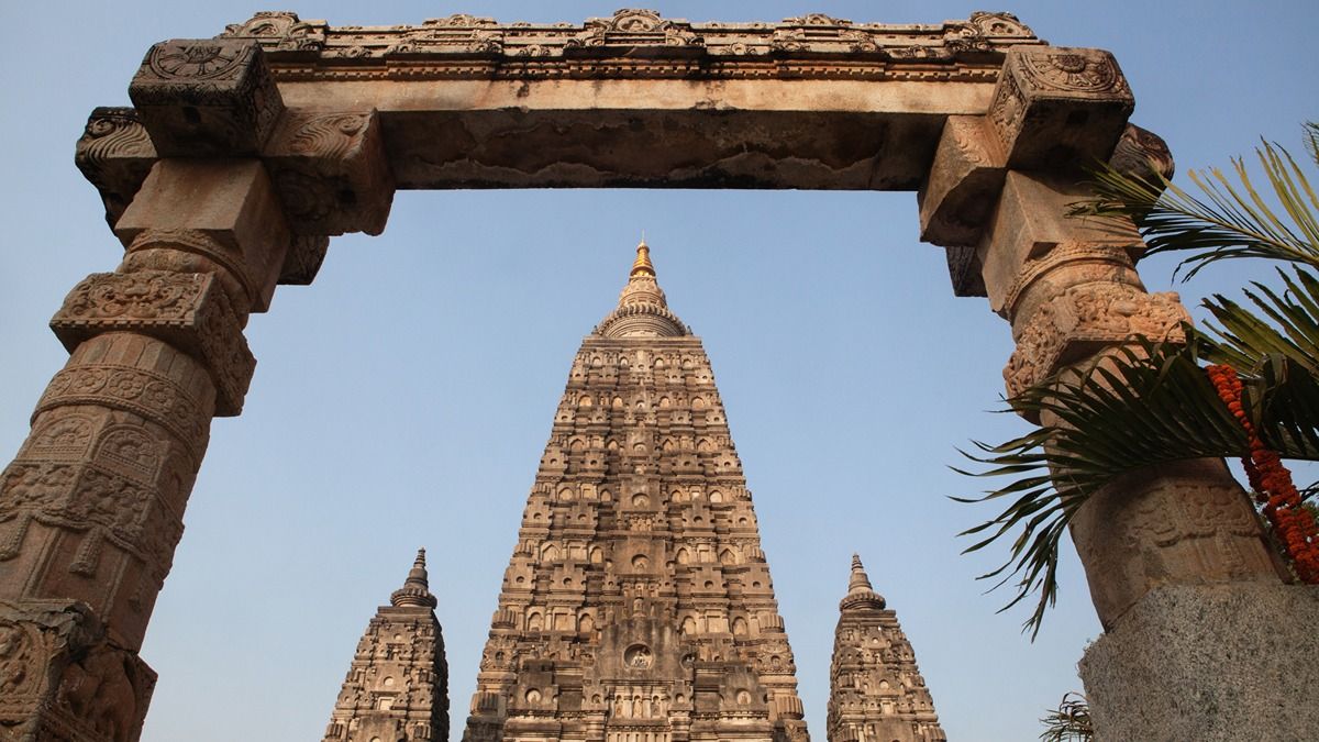 a set of pillars with a tall temple visible in the back