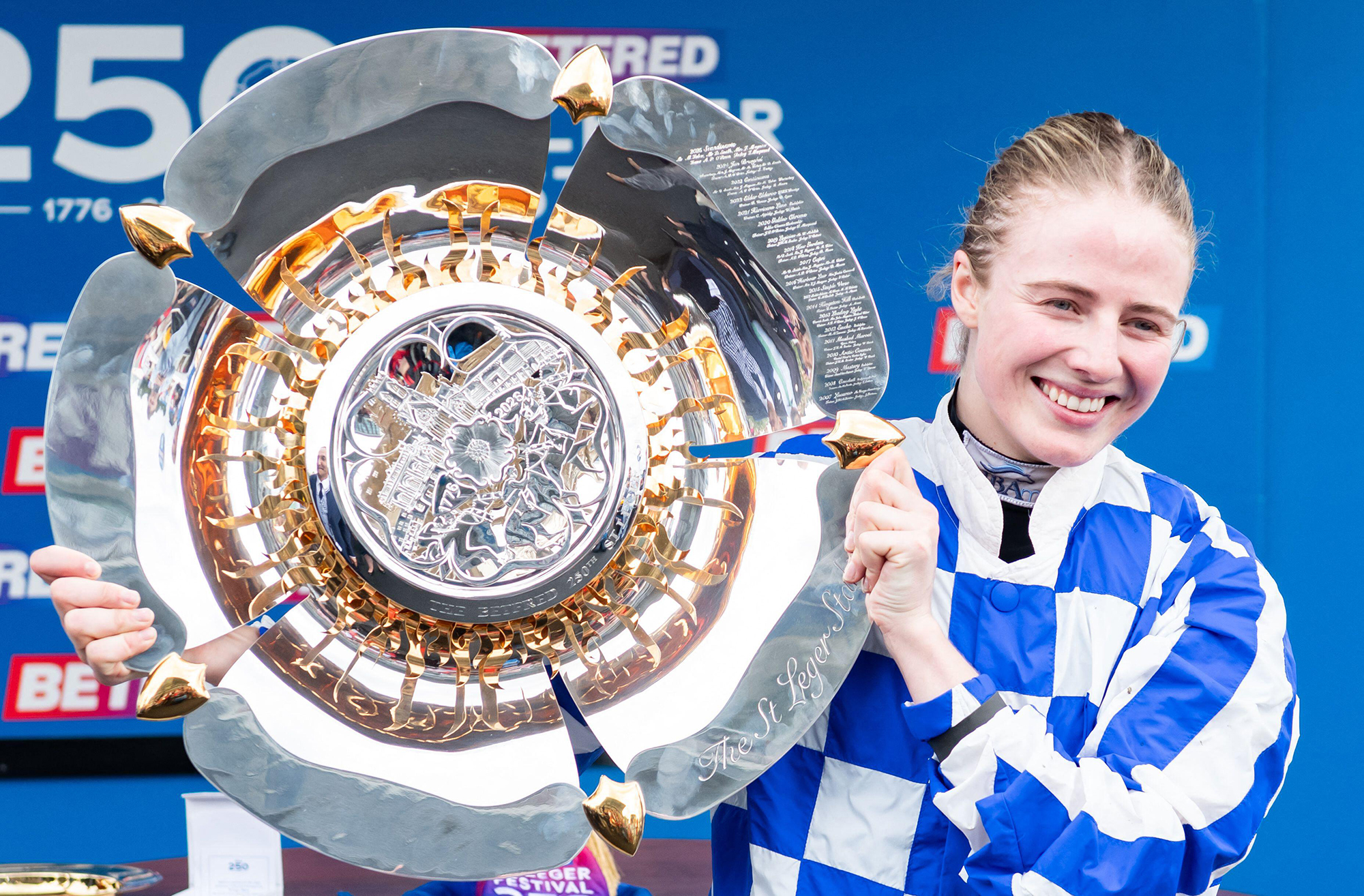 Jockey Saffie Osborne holds the Betfred St Leger Stakes plate trophy after winning on board Highwayman for trainer Joseph O'Brien and owner Mr John I Neocleous.