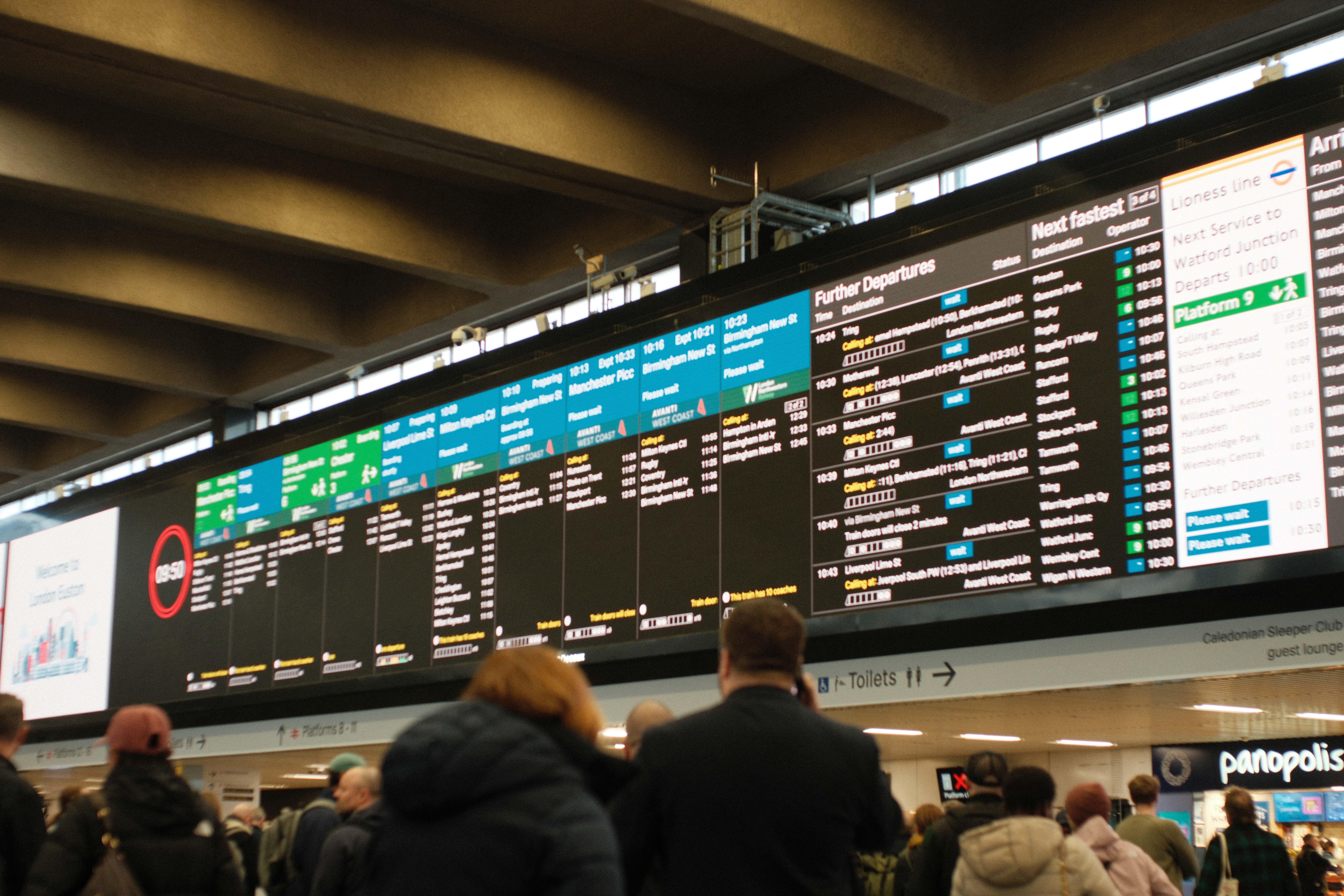 Departure boards above a busy train station concourse