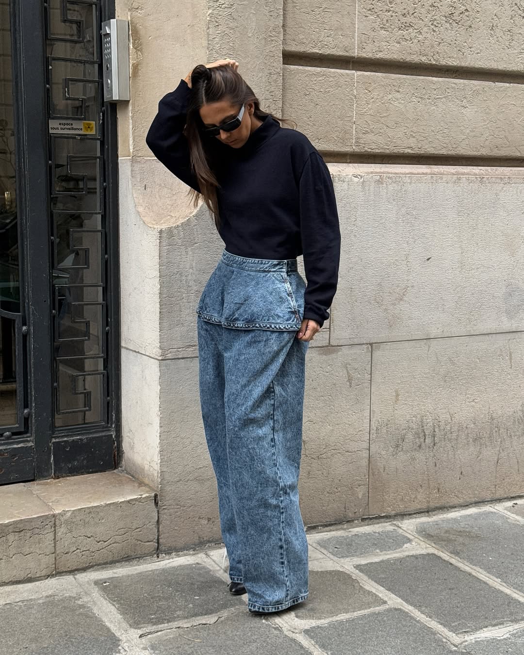 Woman wearing long, baggy jeans fall denim trend 2025.