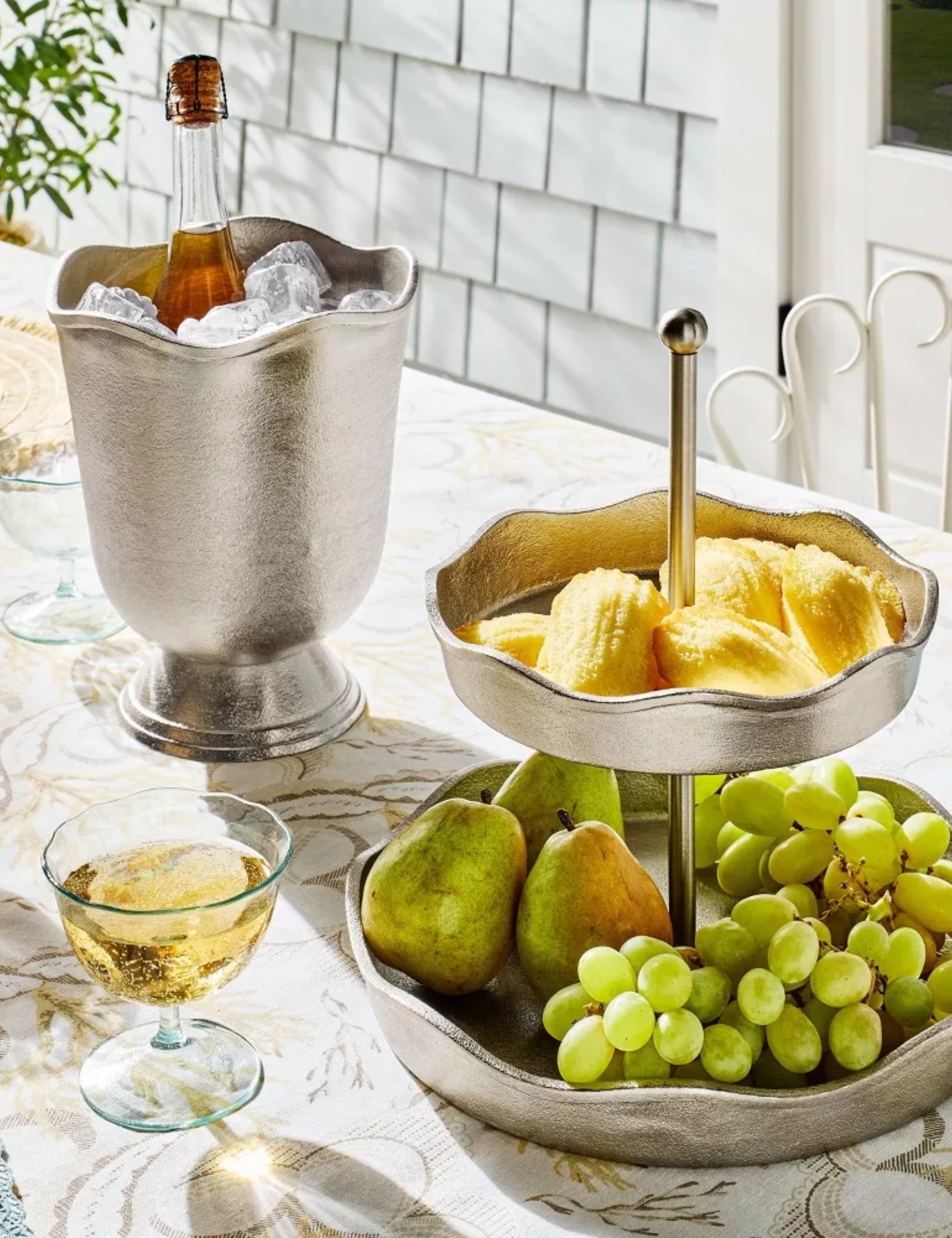 Outdoor tablescape featuring a silver scalloped serving stand and ice bucket, along with a coordinating acrylic cocktail coupe