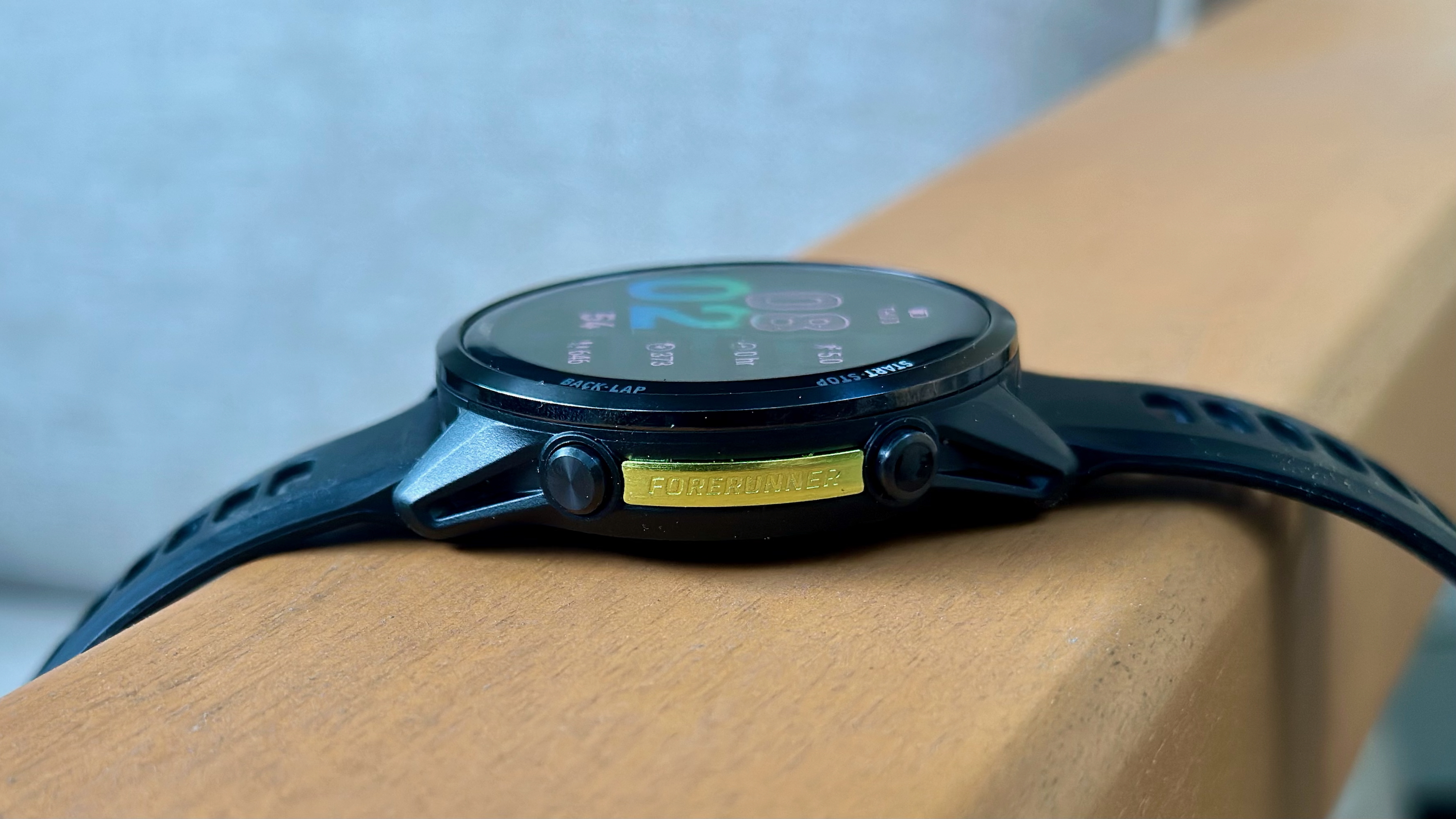 The Garmin Forerunner 970 from a side angle showing the golden "Forerunner" logo and Start / Back buttons.