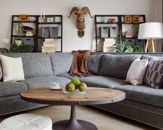 Gray V-shape sofa design in MCM living room, anchored with round, industrial style coffee table.