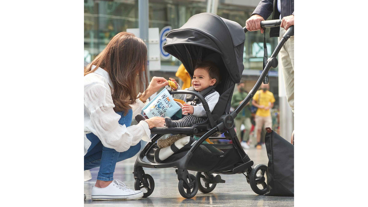 A young woman kneeling down to talk to a baby in the Mamas &amp; Papas Airo pushchair.