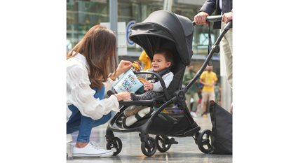 A young woman kneeling down to talk to a baby in the Mamas & Papas Airo pushchair.