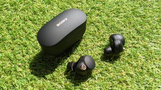 Los sony wf-1000xm4 true wireless earbuds sobre pasto al lado de su estuche