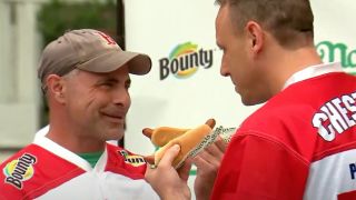 Geoffrey Esper stares down Joey Chestnut with each man holding a hot dog