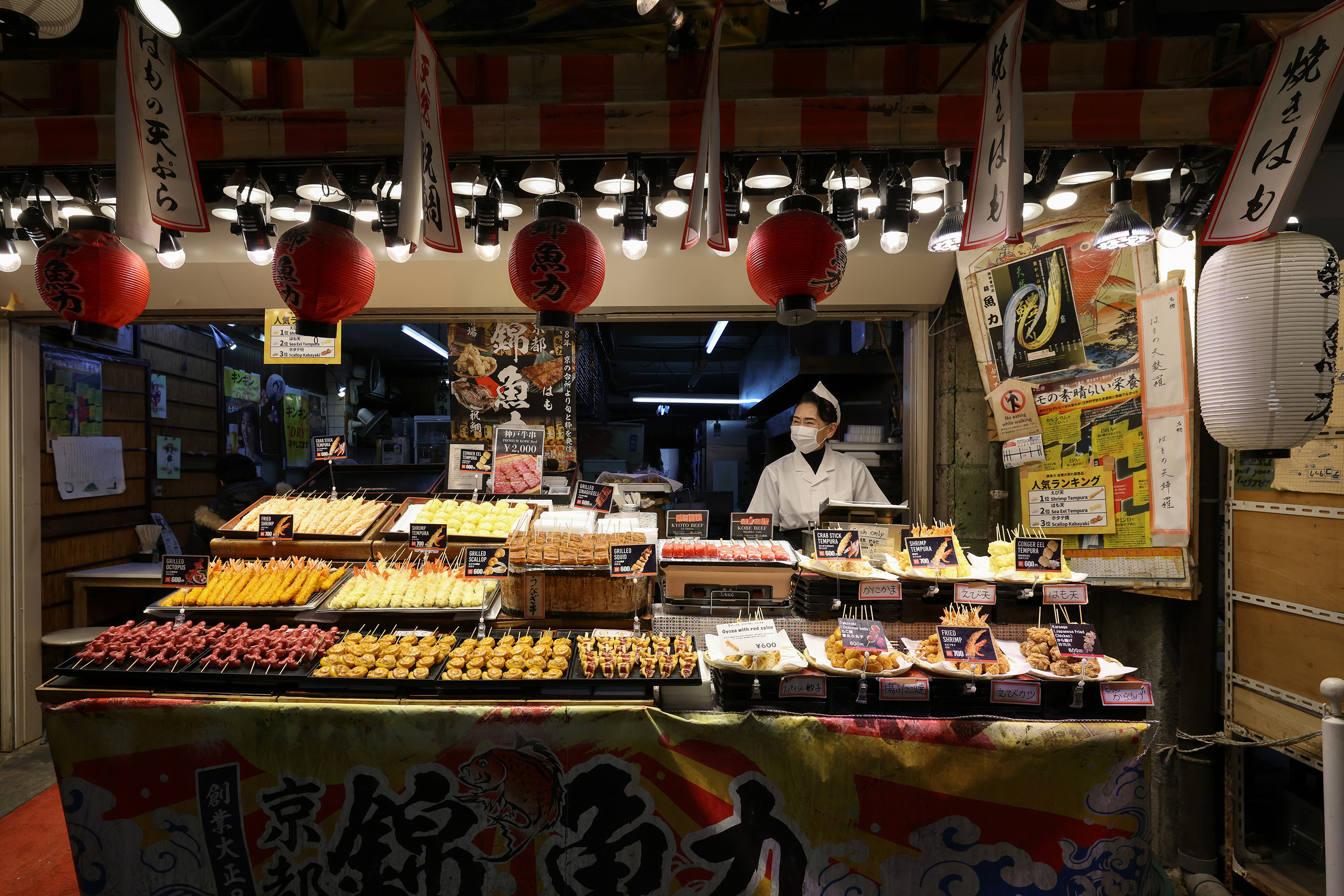 A man stands behind food at the Nishiki Market in Kyoto