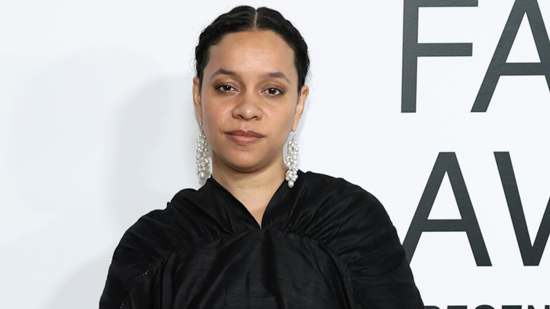 Rachel Scott of Diotima stands on a step and repeat