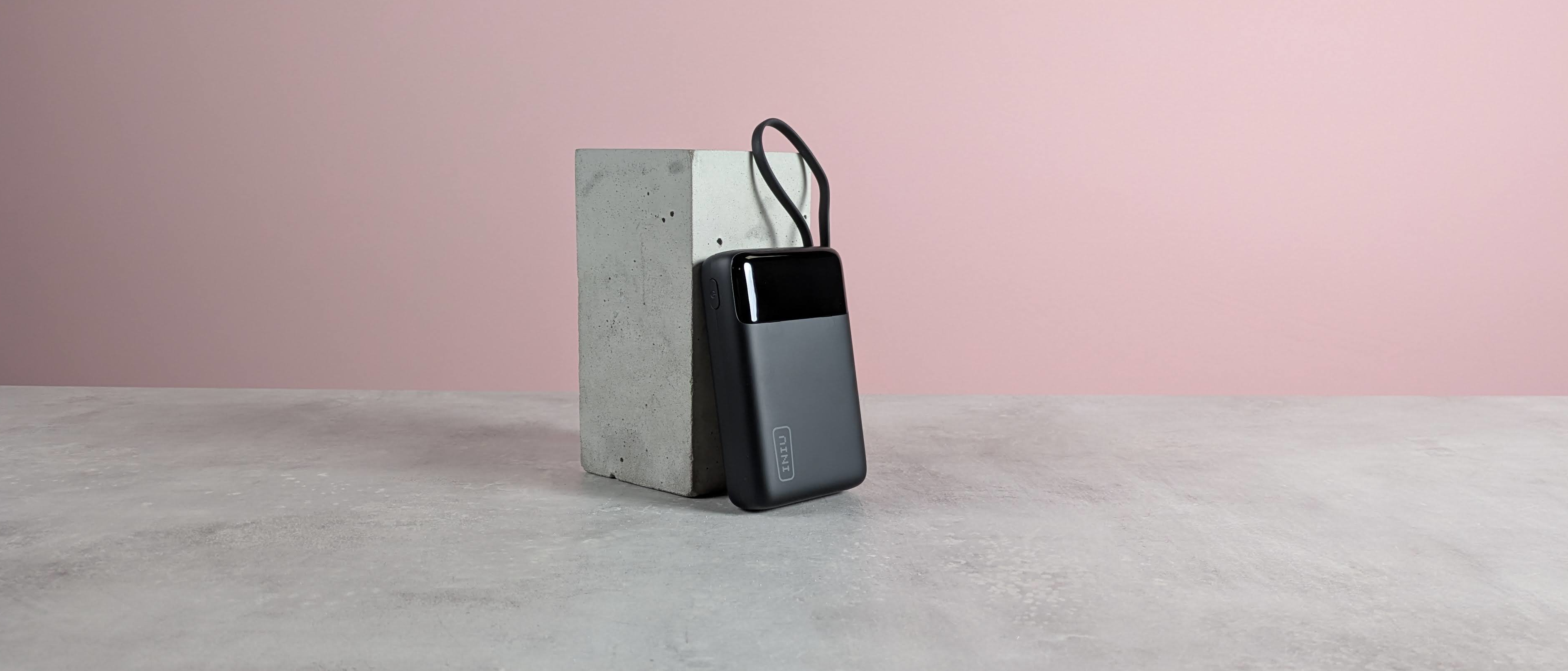 INIU P51L-E1 Power Bank leaning on plinth on desk with pink background