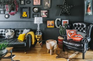 dark living room with black paint walls and leather seating and a contemporary gallery wall
