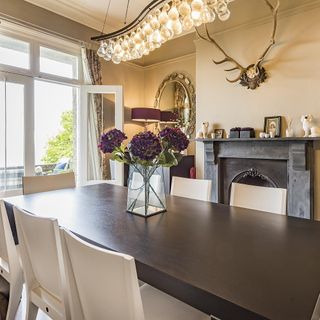 dining room with dark grey table and white chairs with flower on glass jar