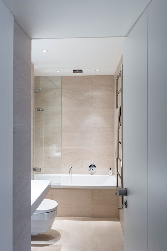 small bathroom with large beige tile and built in speakers