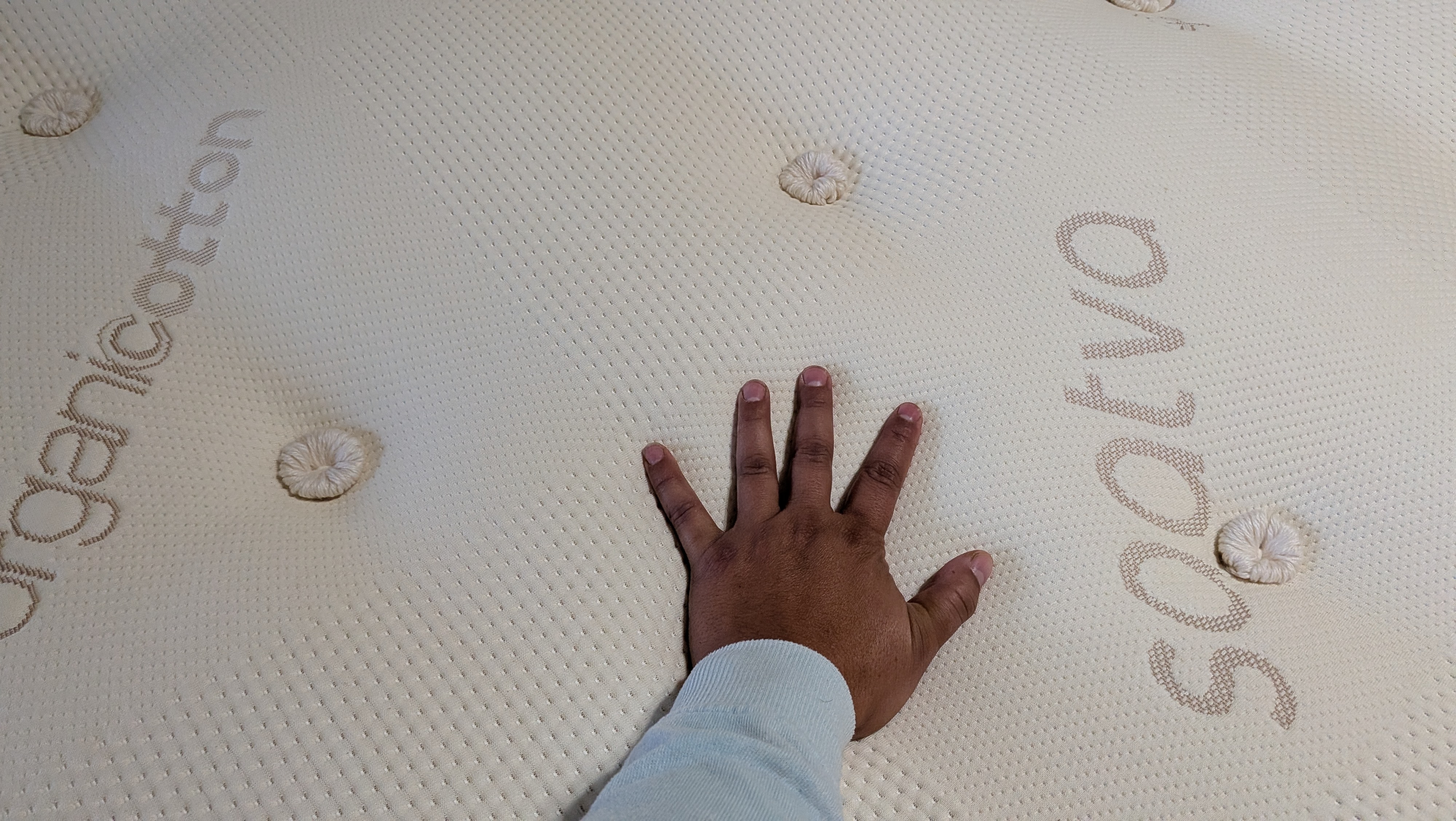 Tester&#039;s left hand on the cover of the Saatva Latex Hybrid Mattress to gauge its coolness