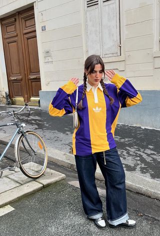 A woman wearing a striped polo with baggy jeans and loafers.