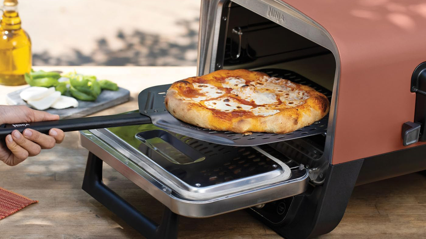 Ninja Woodfire Outdoor Oven with a pizza being removed on a paddle