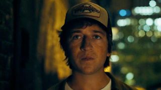 Skyler Gisondo wearing a trucker hat and walking down a dark alley in Superman