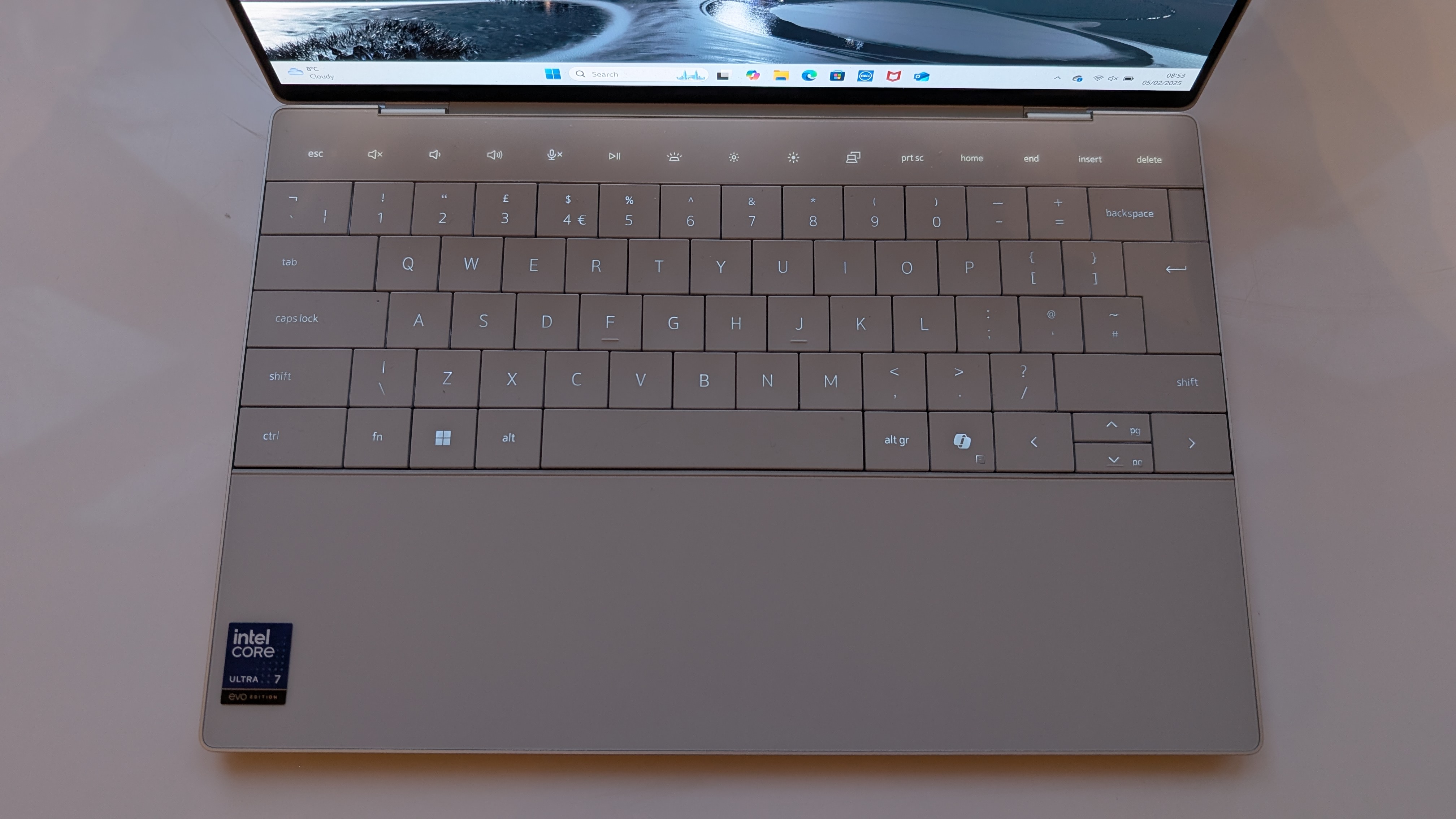 The Dell XPS 13 pictured on a white surface in front of a window with two potted plants.