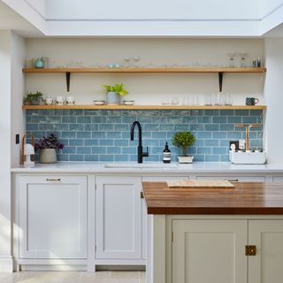 kitchen with blue tiles wall wooden shelf white cabinet and wooden counter
