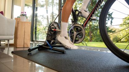rider cycling indoors on a Wahoo trainer, wearing white indoor cycling shoes with white socks
