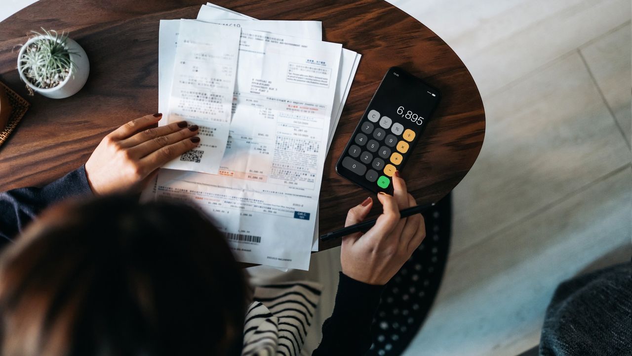 Person sitting at a table with papers and a calculator