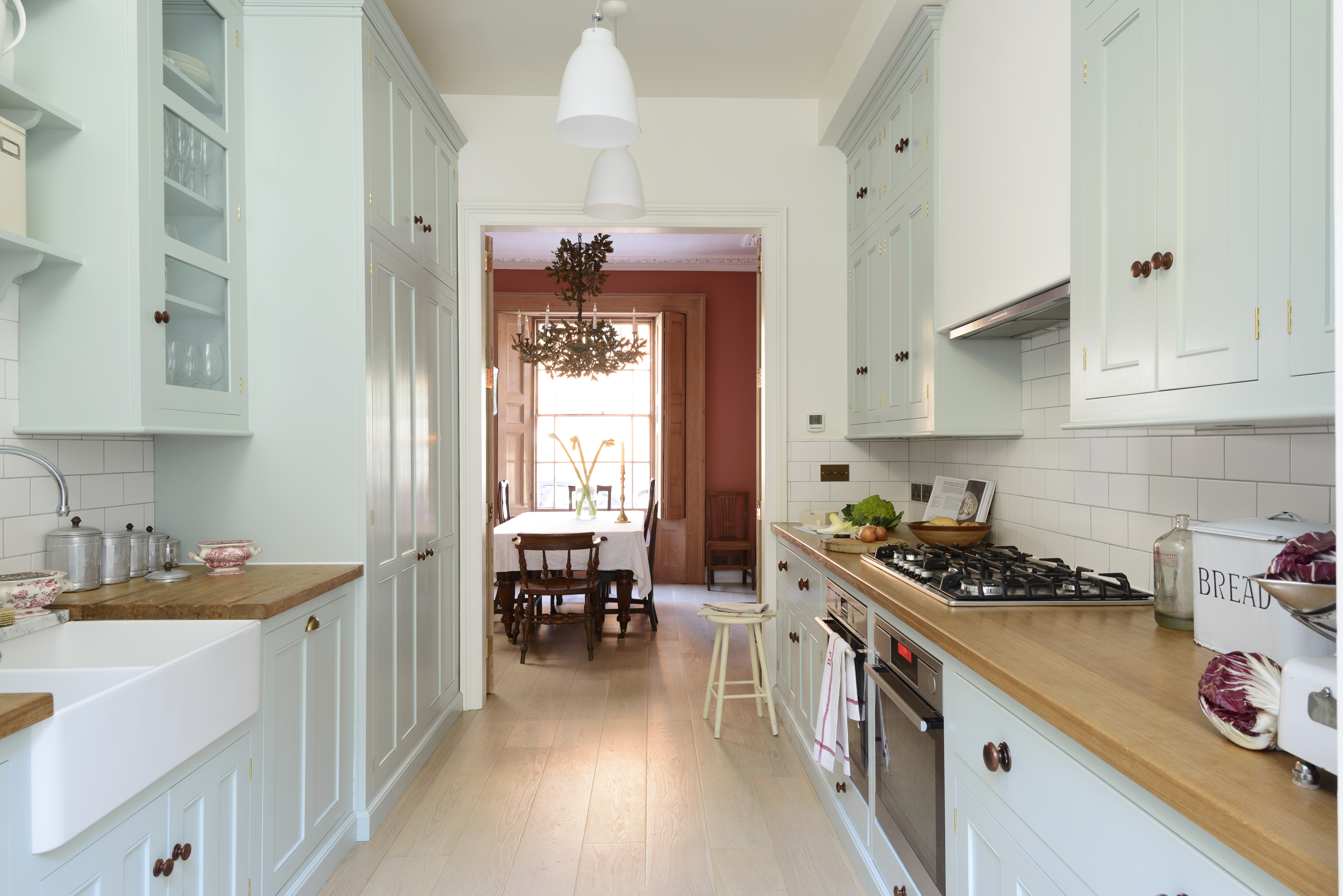 A kitchen with green-toned cabinets that go all the way to the ceiling