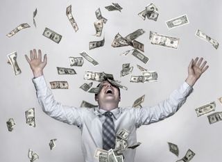 Man throwing dollar bills in the air, arms raised in celebration - stock photo