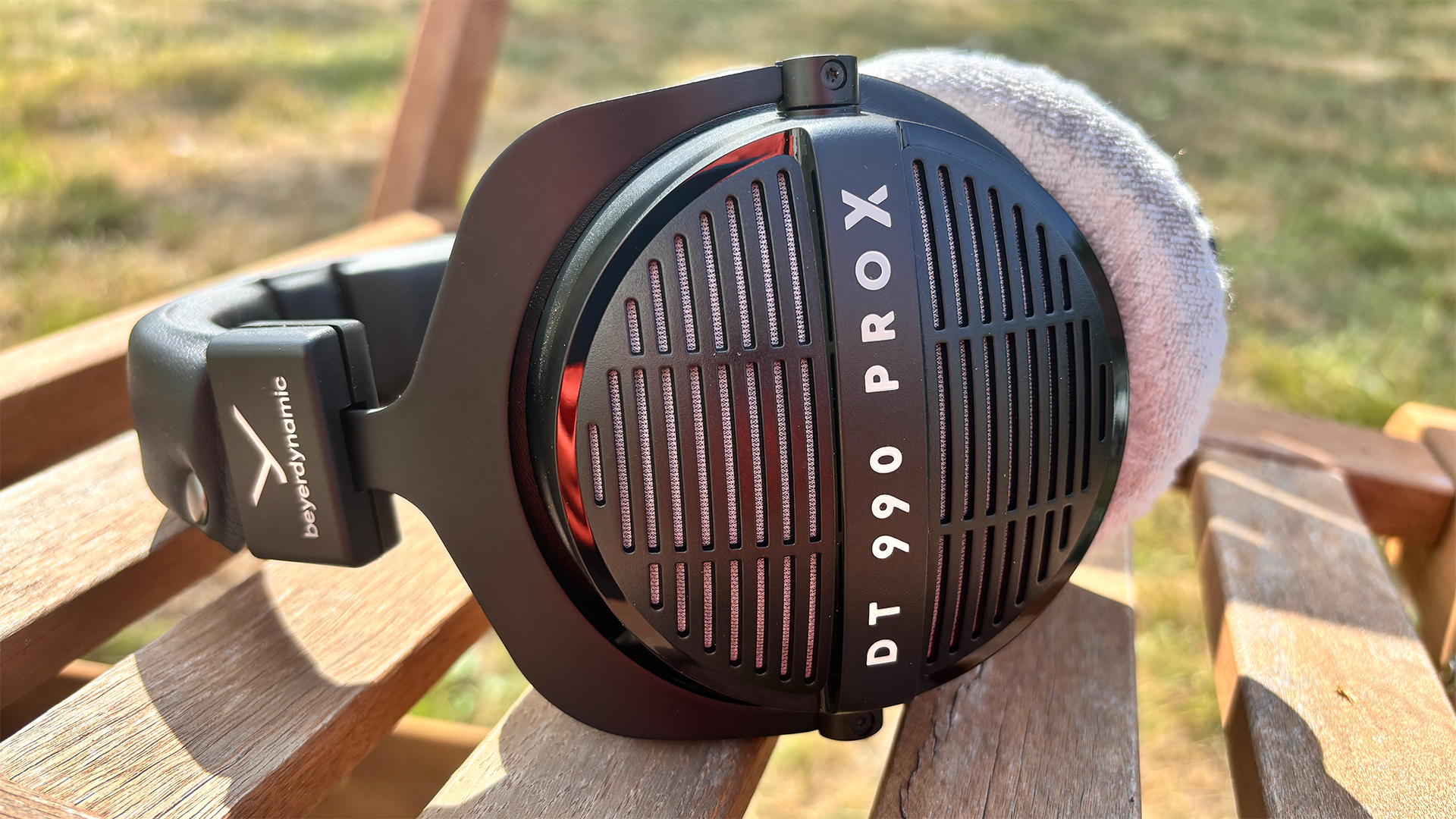 Beyerdynamic DT 990 Pro X wired headphones on wooden garden chair with lawn in background