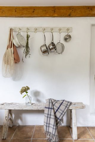 peg rail with pots and pans above a wooden bench in kitchen