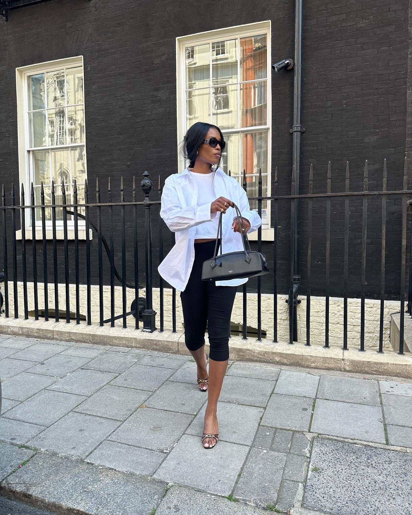 Woman in black capri pants, white tank top, and white button-down.