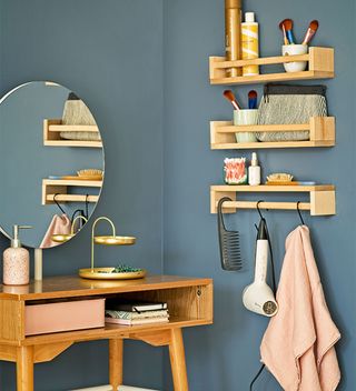 Blue bedroom with wooden dressing table, shelving for make up and products