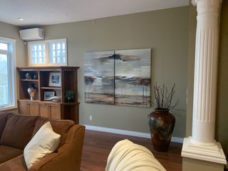 A dated living room with green-gray walls, wooden flooring and a brown sofa