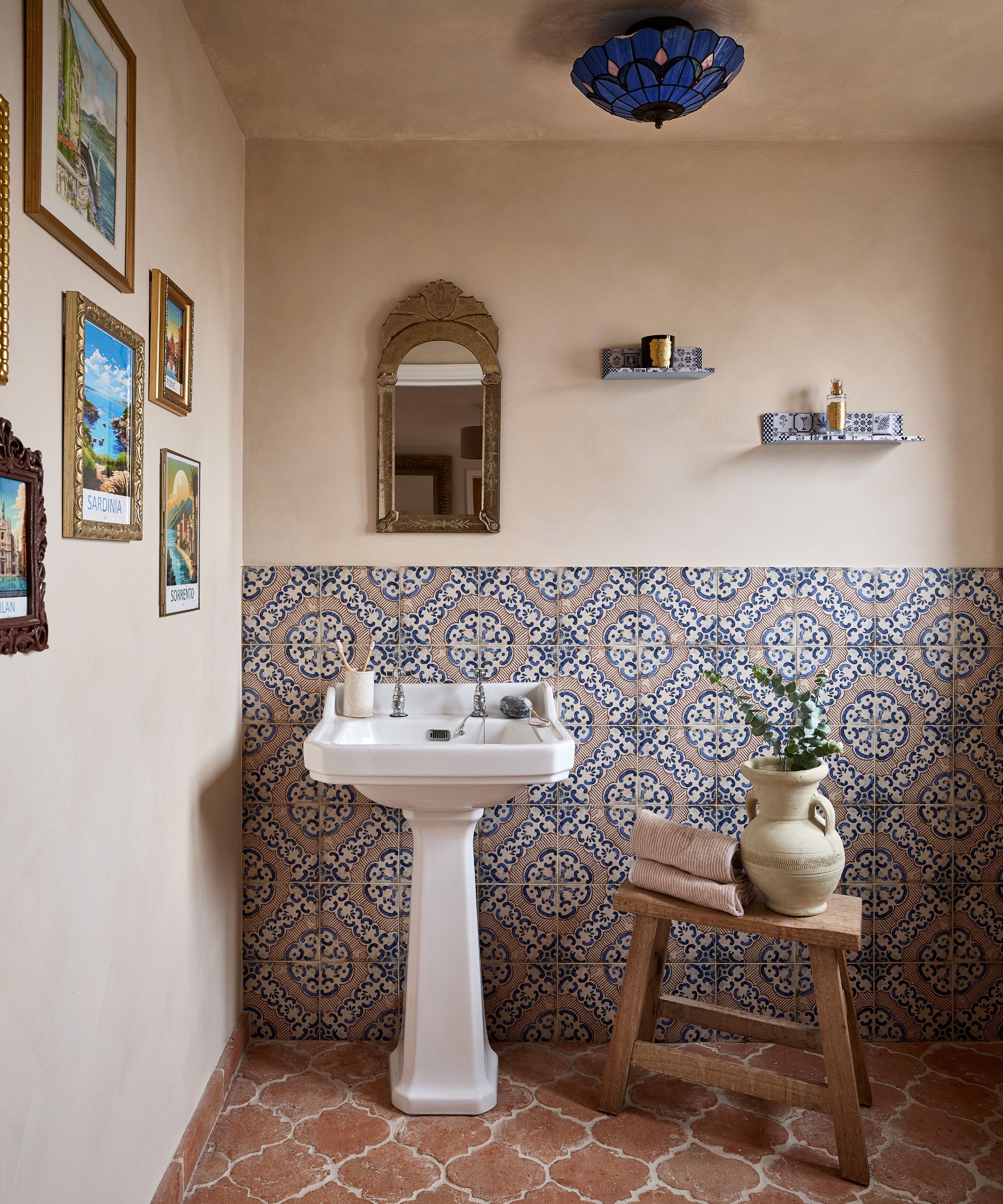 A Mediterranean bathroom with plaster walls, patterned tiles, and terracotta floor tiles