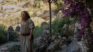 Rory Kinnear as Tom Bombadil standing outside his hut in The Rings of Power.