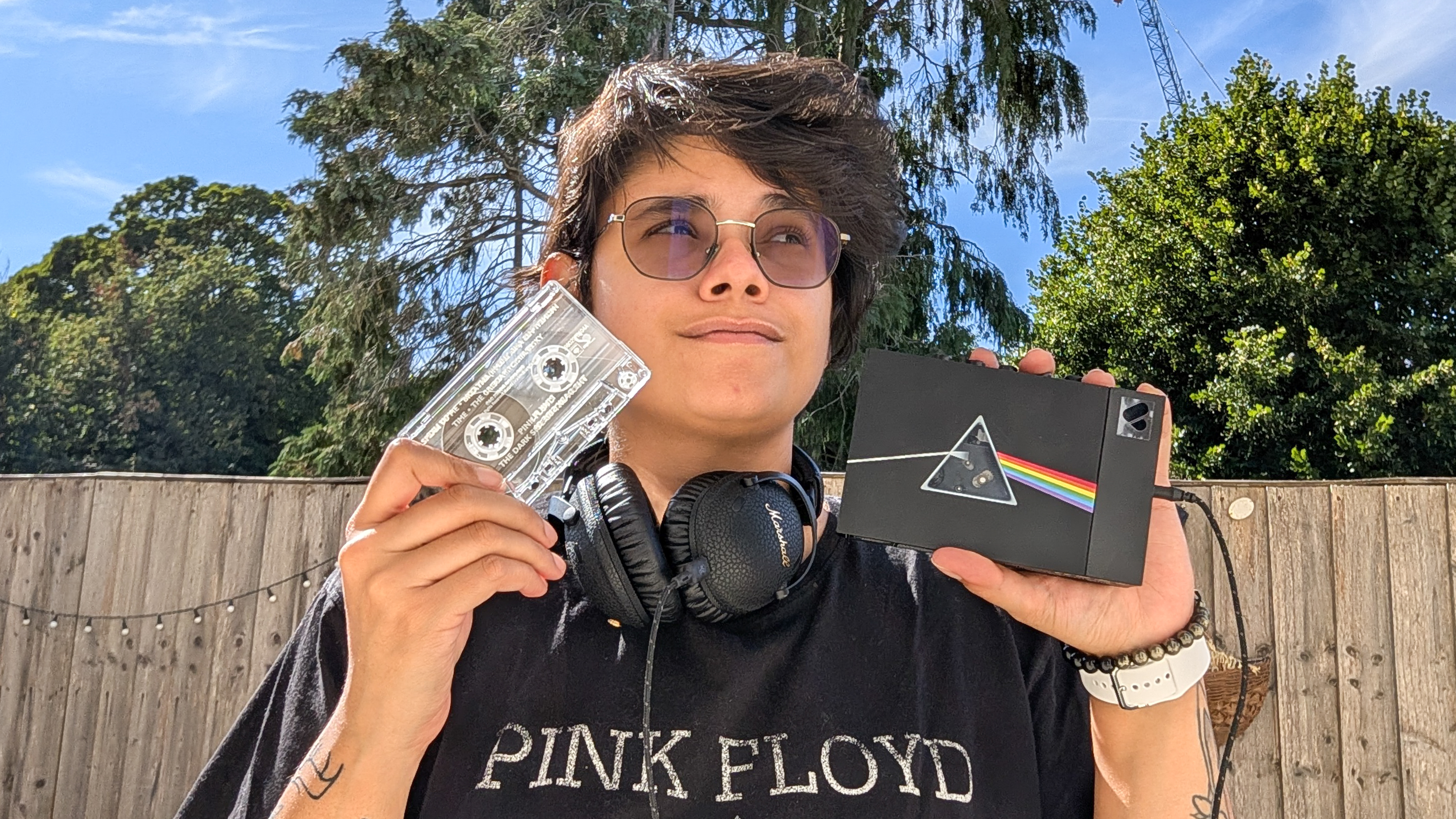 A woman holding a We Are Rewind x Pink Floyd cassette player and a The Dark Side of the Moon cassette
