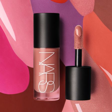 A glass, tube-shaped bottle with the word NARS written in white letters. It also has a black top, and there is a black top with a doe foot applicator next to it.