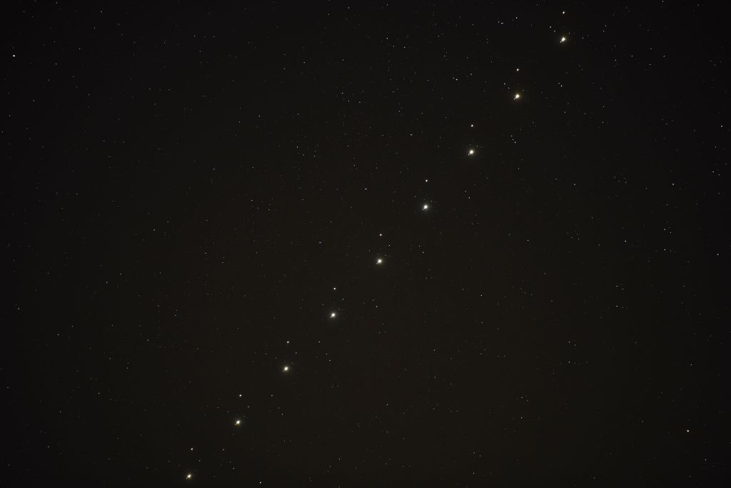 a series of nine images of jupiter and mars conjunction put together in one composition image shows the two points of light travelling up together through the sky, there are some smaller bright points of light close to Jupiter, these are some of the planet's moons.