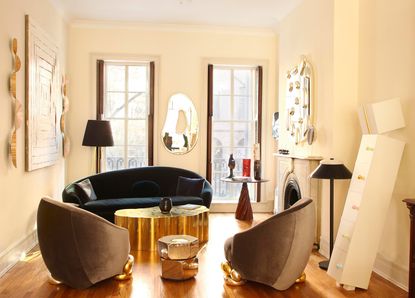 Sitting room in neutral tones and featuring a dark blue sofa and gold coffee table