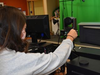 A student sets up a PTZ camera to livestream a school play.