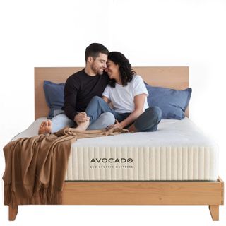 Avocado Eco Green mattress with a man and women sitting on it