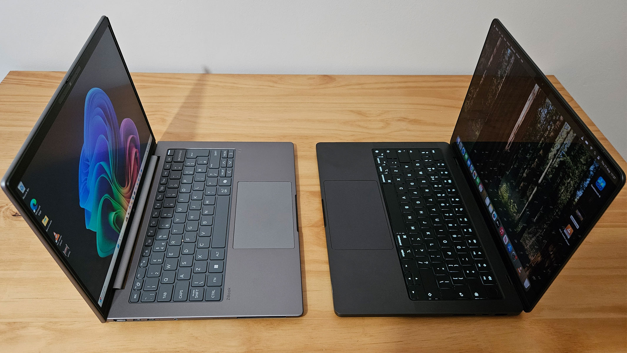 An opened Windows and MacBook facing each other on a wooden table.