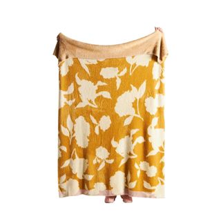 A yellow and white printed blanket being held up
