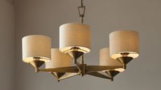 a modern chandelier with brass and linen shades