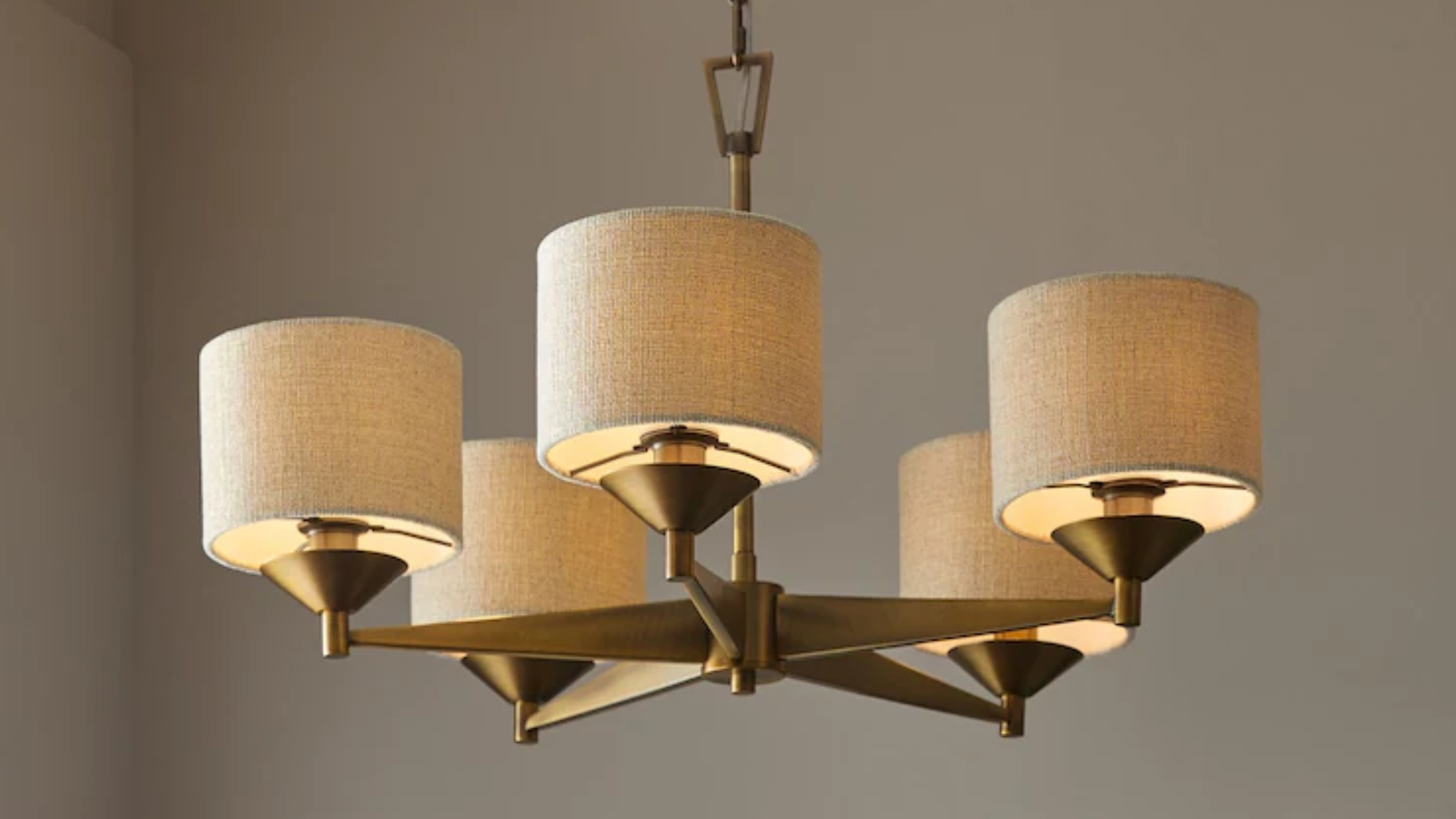 a modern chandelier with brass and linen shades