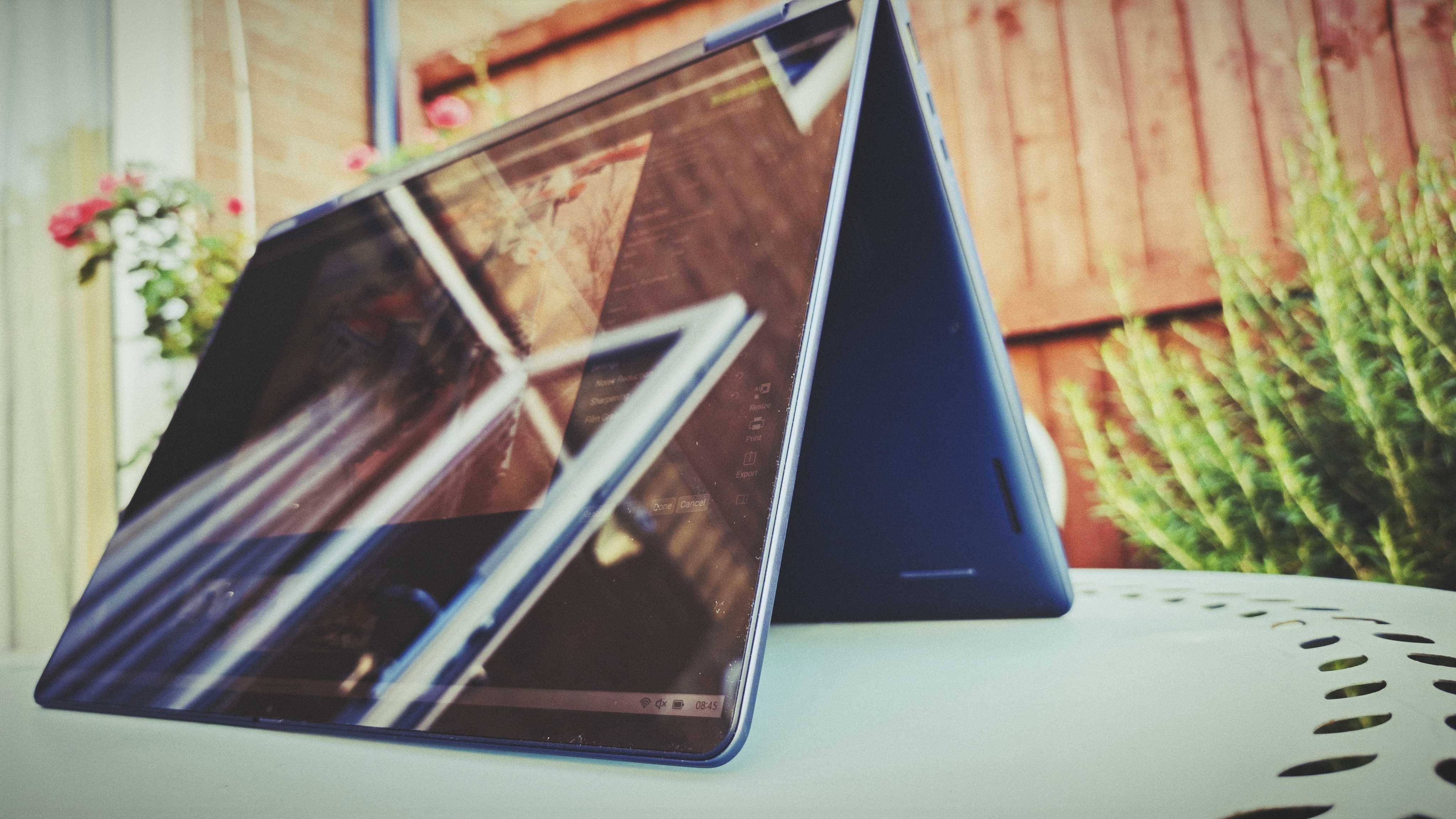 A Dell 16 Plus 2-in-1 laptop on a blue garden table