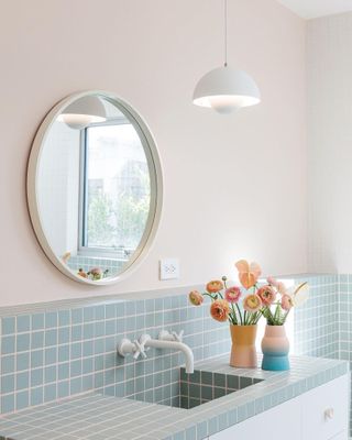 a kids bathroom with blue tiles and pink grout