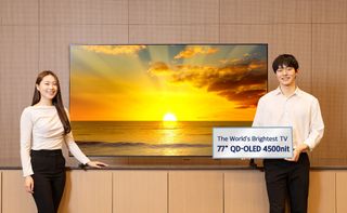 Two models in white tops and black trousers show a 77-inch Samsung 2026 QD-OLED panel TV