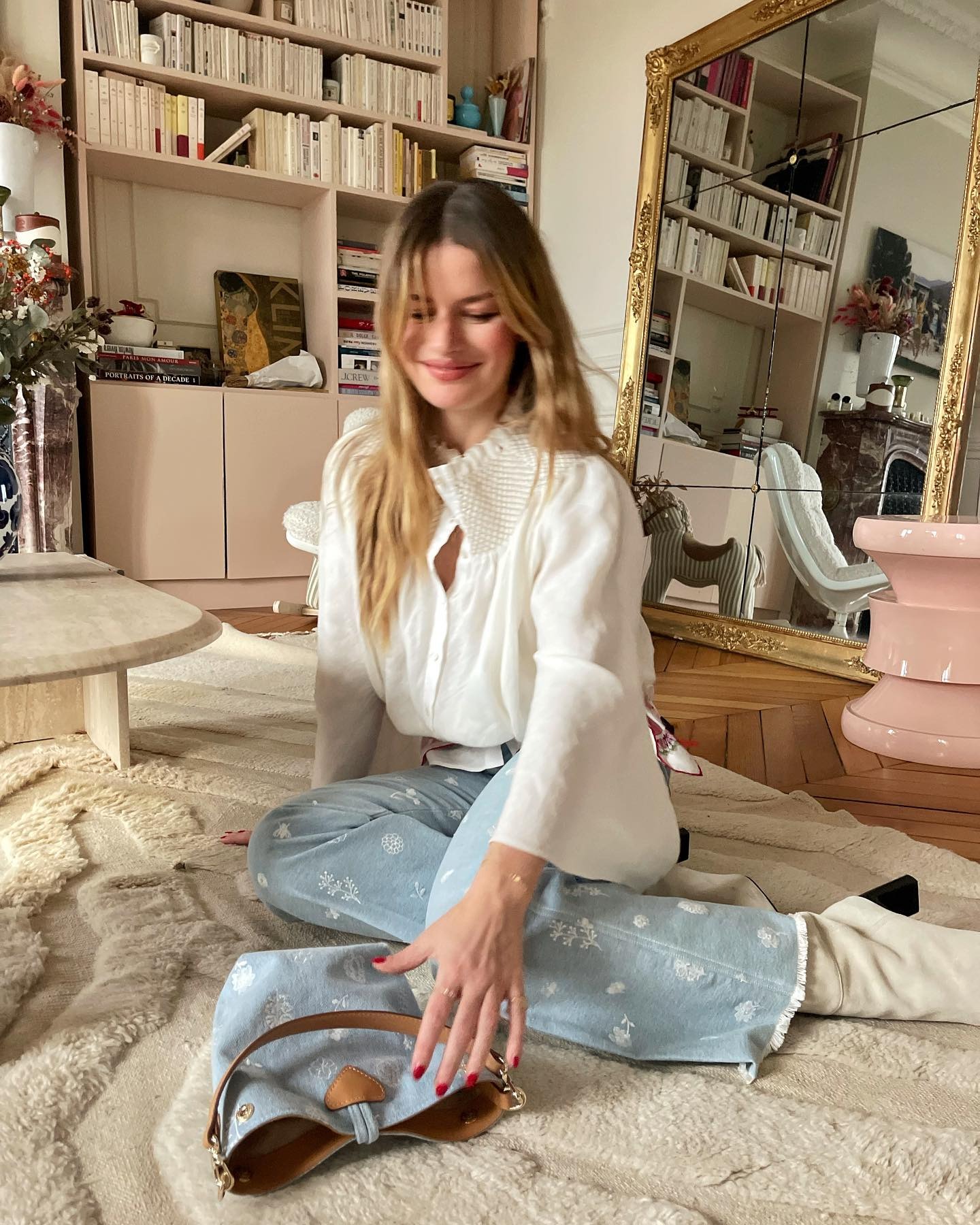 A woman in Paris sitting on her living room floor with a deep red manicure